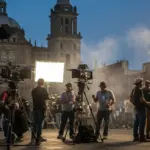 Equipo de producción cinematográfica filmando en una locación vibrante en México, con edificios históricos de fondo, simbolizando el impacto de los incentivos fiscales.