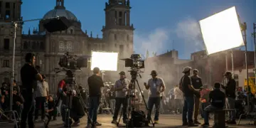Equipo de producción cinematográfica filmando en una locación vibrante en México, con edificios históricos de fondo, simbolizando el impacto de los incentivos fiscales.